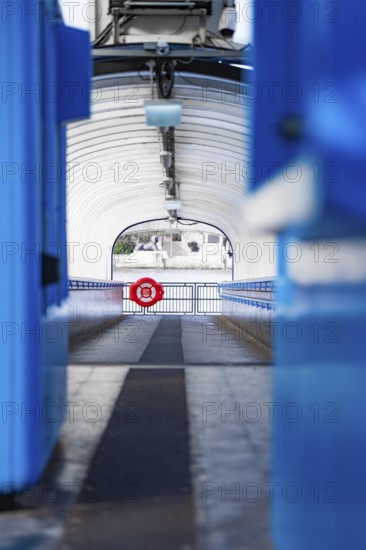 A modern, symmetrical corridor with blue elements leads outside, across boat, London, England, Great Britain