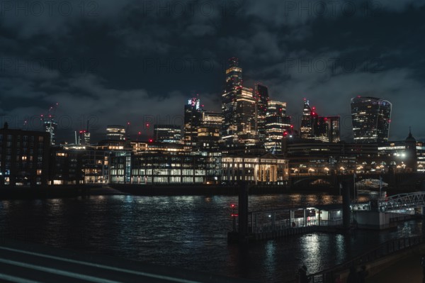 Illuminated skyline of a city at night over a river surrounded by skyscrapers and bridges, London, England, Great Britain