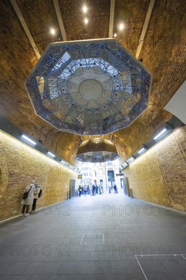 An artistically designed brick vault with lettering and people in an urban space, London Bridge Station, London, United Kingdom