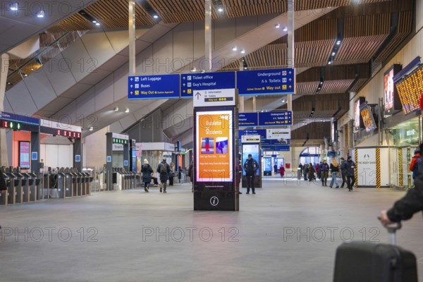 Bright and modern train station with digital displays and various travelers, London, United Kingdom