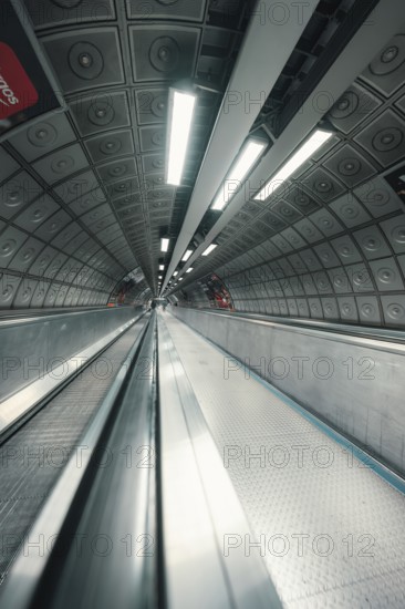A subway tunnel with escalator and futuristic atmosphere through lighting and architecture, London, United Kingdom