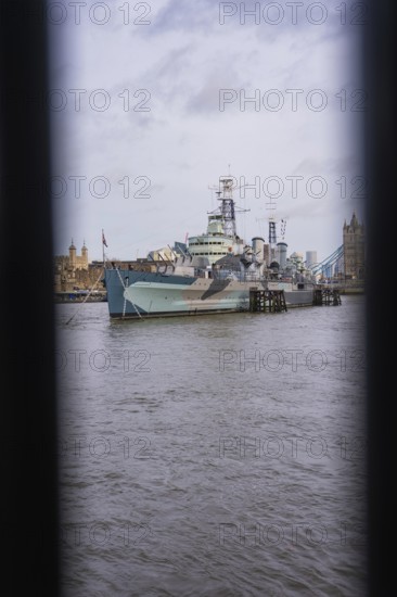 View between two structures of a ship in the river in front of historic towers, HMS Belfast, London, United Kingdom