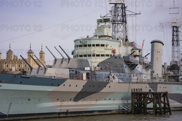 Detailed view of a historic warship with guns, towers in the background, HMS Belfast, London, United Kingdom