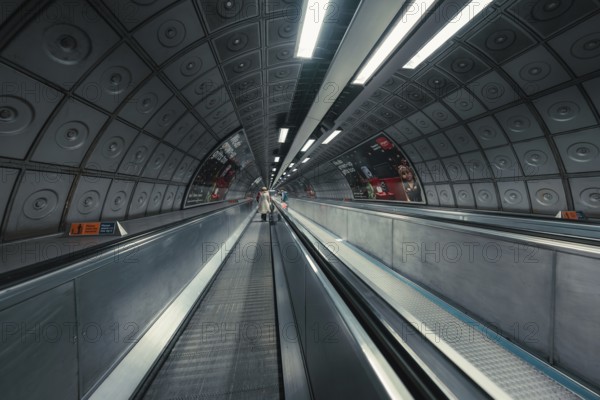 Long subway tunnel with escalator, symmetrical design and modern lighting, London, United Kingdom