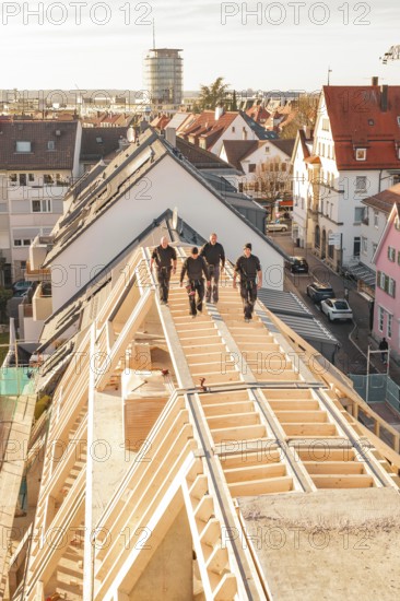 Craftsmen walking on a roof of a new building in an urban environment, carpentry, renovation, roof extension, Stuttgart, Germany