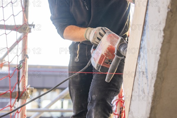 Close-up of a craftsman with a drill on a construction site, carpentry, renovation, roof extension, Stuttgart, Germany