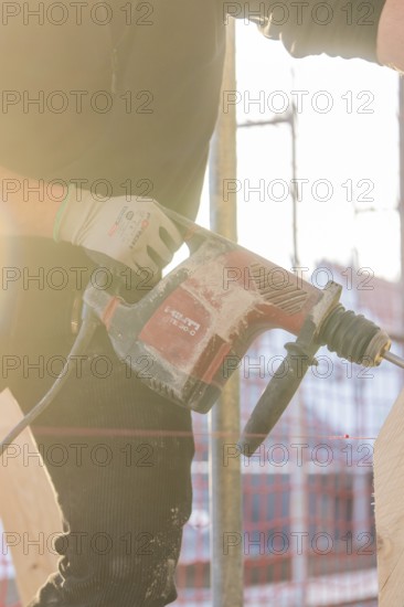 Craftsman with drill during construction work in backlight, carpentry, renovation, roof construction, Stuttgart, Germany