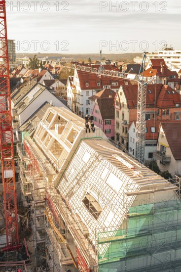Urban construction on a roof with a crane and surrounding houses, carpentry, renovation, roof extension, Stuttgart, Germany