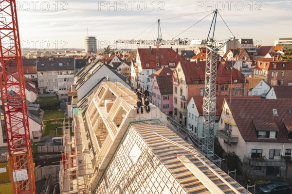 Workers on a half-finished roof surrounded by varied urban development, carpentry, renovation, roof extension, Stuttgart, Germany