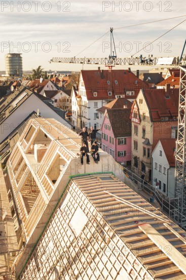 Group of workers on a roof in a lively urban environment with a crane, carpentry, renovation, roof extension, Stuttgart, Germany