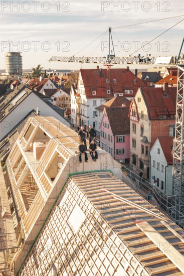 Craftsmen posing on the roof top of a new building in an urban environment, carpentry, renovation, roof extension, Stuttgart, Germany