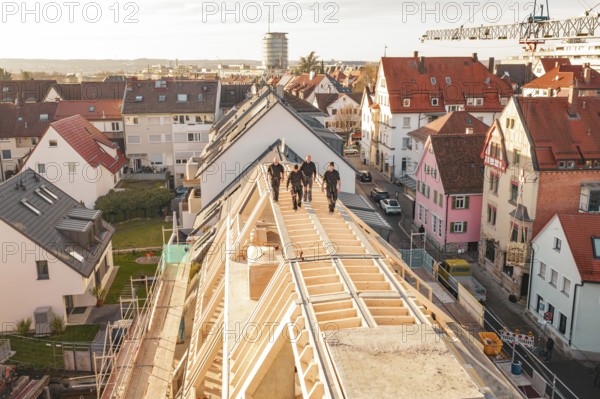 Workers on a new roof with a view of a colorful urban environment, carpentry, renovation, roof extension, Stuttgart, Germany