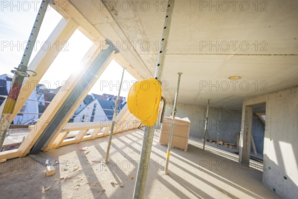 Construction site with yellow helmet on support, light concrete walls and wooden frame, carpentry, renovation, roof extension, Stuttgart, Germany