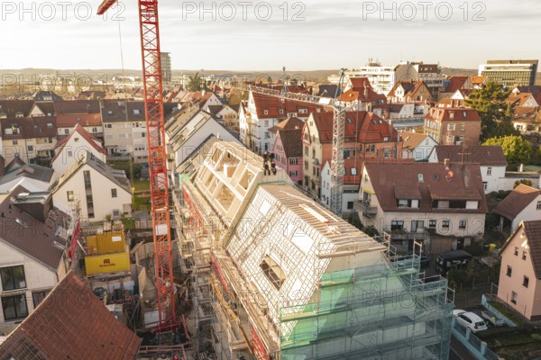 Construction site on a roof in the city with crane and surrounding houses, carpentry, renovation, roof extension, Stuttgart, Germany