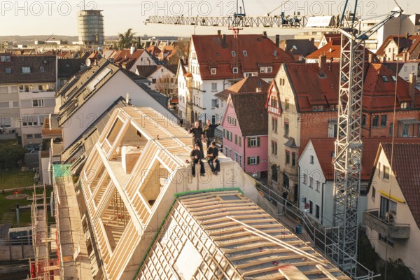 Craftsmen enjoy the view from a new roof in a dense residential area, carpentry, renovation, roof extension, Stuttgart, Germany