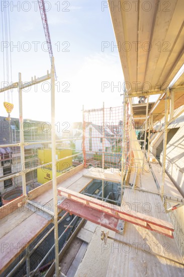View from above of a construction site with scaffolding at sunset. Urban environment visible, carpentry construction site, roof extension, renovation, Stuttgart, Germany