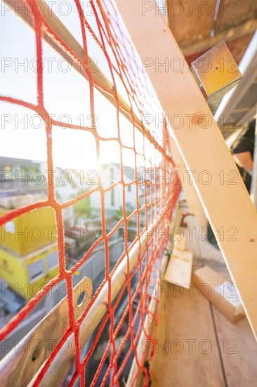 Red safety net on a railing allows sunlight to fall into a construction site, carpentry construction, roof extension, renovation, Stuttgart, Germany