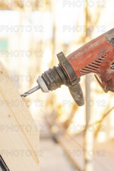 A drill drills into a slanted piece of wood, illuminated by sunlight, carpentry construction, roof extension, renovation, Stuttgart, Germany