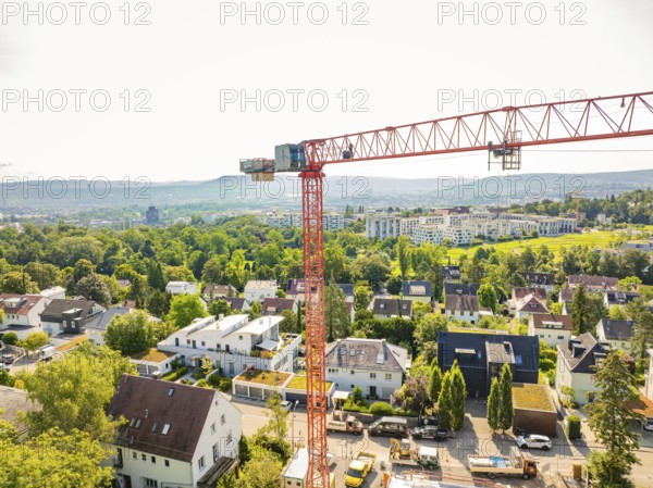 Crane over an urban residential area with green areas and a wide view, construction site of a carpentry workshop, roof extension, renovation, Stuttgart, Germany