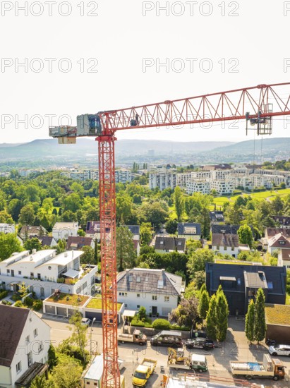 View of a large crane over a residential area in front of a mountainous landscape, construction site of a carpentry workshop, roof extension, renovation, Stuttgart, Germany