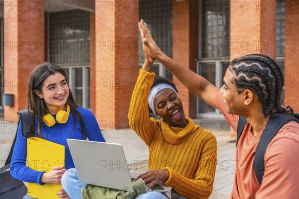 Diverse group of university students on campus sharing a triumphant high five, smiling and celebrating teamwork, achievement and positive energy during study and campus life