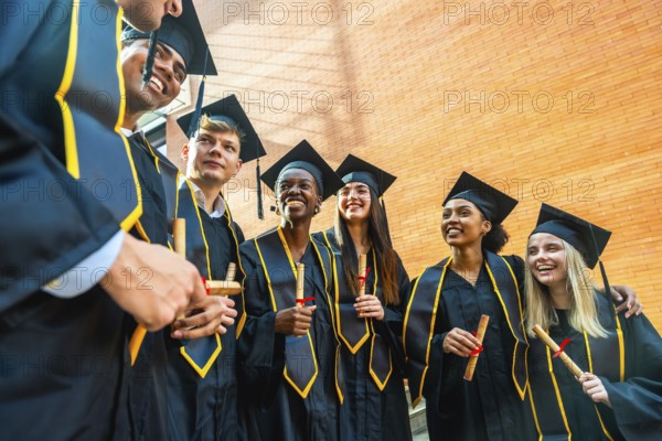 Diverse students wearing graduation gowns and caps, smiling while holding diplomas, celebrating achieving their college education and looking forward to their future careers