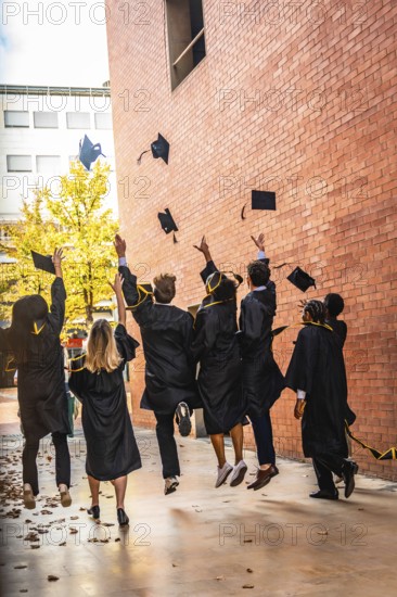 Diverse group of university students celebrating an achievement and success by throwing graduation caps into the air, symbolizing freedom and the future in an outdoor setting