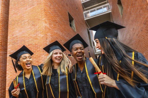 Diverse group of happy female students celebrating their university graduation, proudly wearing caps and gowns while holding diplomas and expressing joy and friendship outdoors