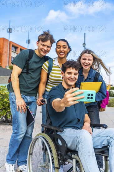 Group of happy diverse university students, including a person using a wheelchair, smiling and taking a cheerful selfie together on campus, representing friendship and inclusion