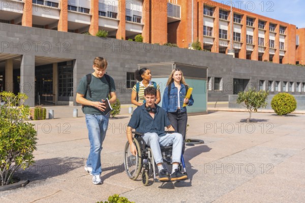 Multi ethnic group of university students, including a wheelchair user, walking and chatting on campus sidewalk by modern building, showcasing inclusion, accessibility and friendship