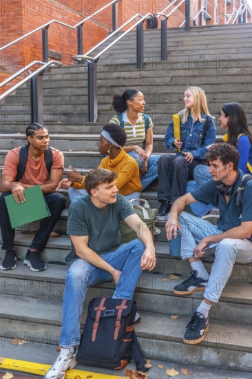 Diverse group of university students sitting on urban campus stairs, chatting, studying and laughing together modern, multiethnic college friends connecting, learning and relaxing outdoors