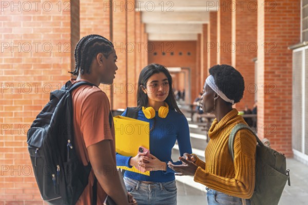 Three diverse university students are having a friendly conversation in a campus corridor, reflecting camaraderie and connection within an educational setting