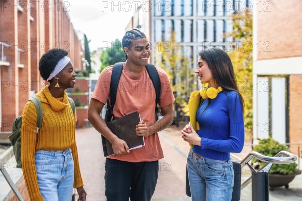 Three diverse students walking together and enjoying a conversation while moving through a modern university campus building, representing friendship, education, and student life