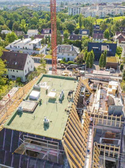 Top view of a building with a crane in an urban environment with lots of greenery, carpentry construction, roof extension, renovation, Stuttgart, Germany