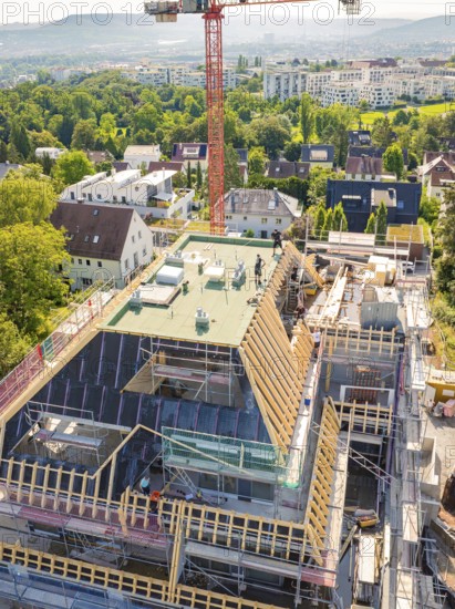 Construction of a multi-storey building with crane and scaffolding in a green urban environment, carpentry construction, roof extension, renovation, Stuttgart, Germany