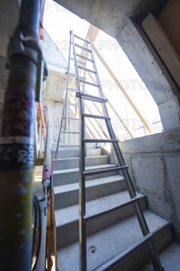 A steel staircase leads to a ladder under a concrete opening that leads upwards, carpentry construction, roof extension, renovation, Stuttgart, Germany