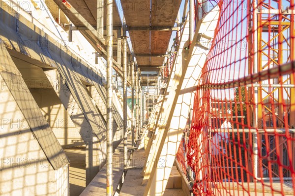 A scaffolding with wooden panels and casting shadows on a construction site, carpentry construction, roof extension, renovation, Stuttgart, Germany