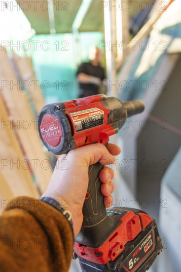 A worker holds a red electric screwdriver in a construction site situation, carpentry construction, roof removal, renovation, Stuttgart, Germany