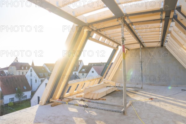 An unfinished roof truss with a view of a settlement at sunrise, construction of a carpentry workshop, roof extension, renovation, Stuttgart, Germany