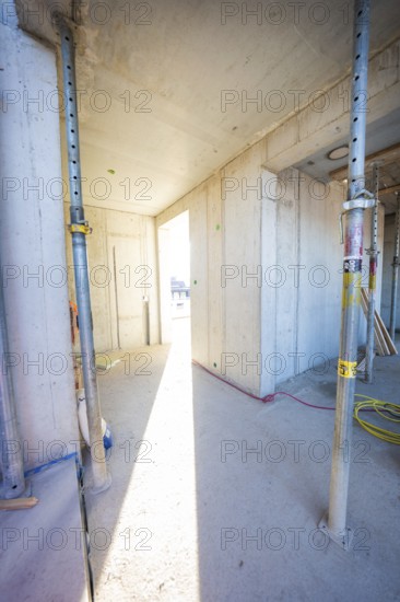 A sunlit corridor in an unfinished building with concrete walls and metal supports, carpentry construction, roof extension, renovation, Stuttgart, Germany