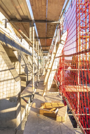 A scaffolding with wooden panels and casting shadows on a construction site, carpentry construction, roof extension, renovation, Stuttgart, Germany