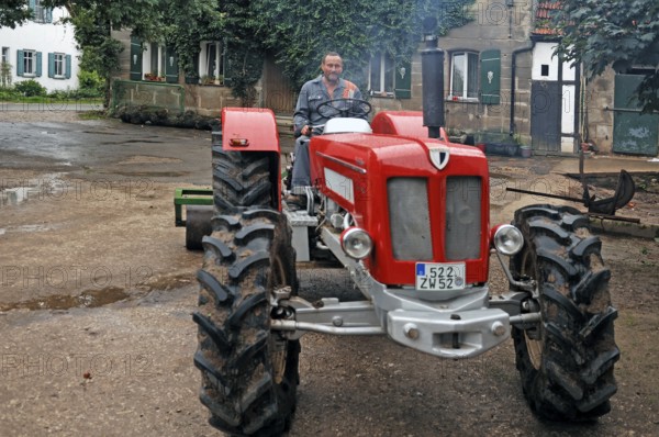 Farmer on his new Schlüter tractor in the yard, Tauchersreuth, Middle Franconia, Bavaria, Germany