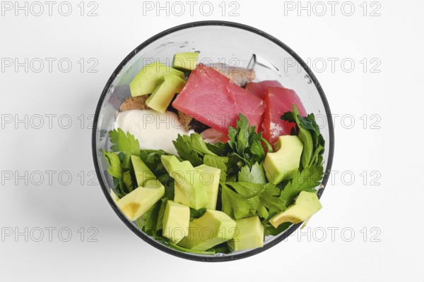 Smoked tuna fillets, avocado, greek yoghurt and parsley in a bowl of hand blender. This healthy mixture is ready for blending into a nutritious paste