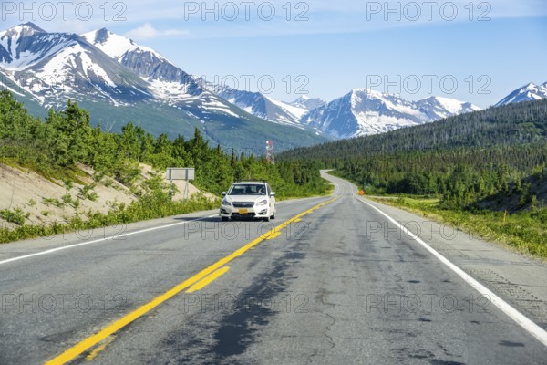 Car on road through taiga and mountainous landscape, picturesque landscape on Richardson Highway, Alaska, USA