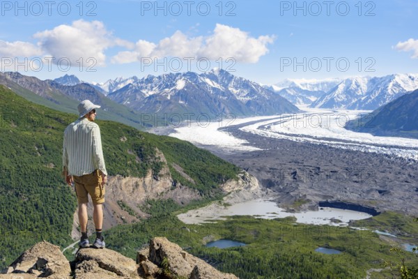 Young man enjoying the view, view of impressive mountain landscape with Matanuska glacier and glaciated mountain peaks, Lion's Head, Chugach Mountains, Alaska