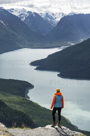 Female mountaineer enjoying views of blue lake and mountains on Twin Peaks Trail, Eklutna Lake, Chugach Mountains, Chugach State Park, Alaska, USA