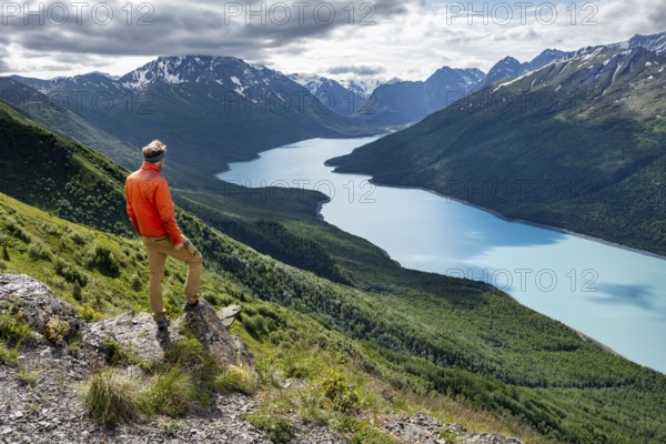Mountaineer enjoys views of blue lake and mountains on Twin Peaks Trail, Eklutna Lake, Chugach Mountains, Chugach State Park, Alaska, USA