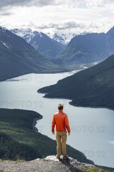 Mountaineer enjoys views of blue lake and mountains on Twin Peaks Trail, Eklutna Lake, Chugach Mountains, Chugach State Park, Alaska, USA