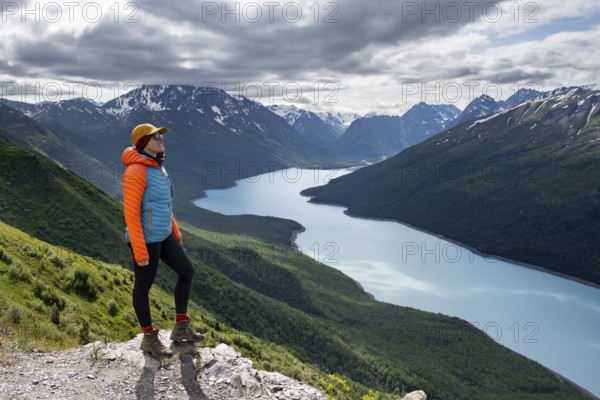 Female mountaineer enjoying views of blue lake and mountains on Twin Peaks Trail, Eklutna Lake, Chugach Mountains, Chugach State Park, Alaska, USA