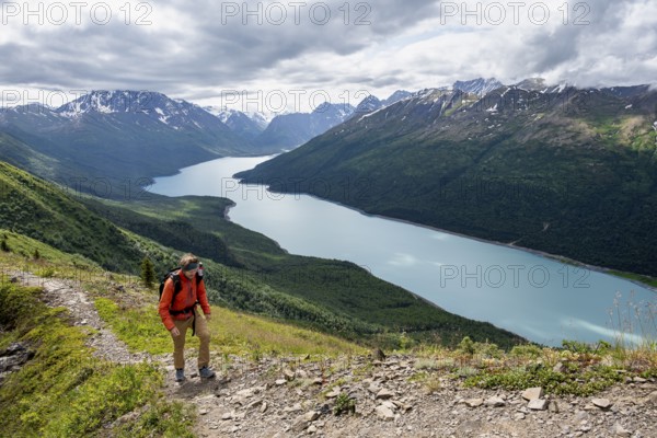 Climbers on a hiking trail, view of blue lake and mountains on Twin Peaks Trail, Eklutna Lake, Chugach Mountains, Chugach State Park, Alaska, USA